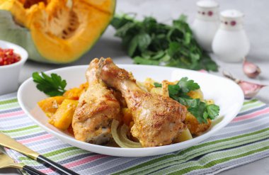 Kabaklı tavuk budu, sarımsak ve beyaz tabakta patates.