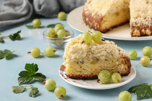 Homemade shortbread pie with green gooseberries and cut piece on plate on light blue background