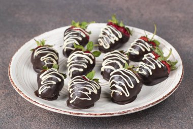 Kahverengi arka planda çikolata kaplı lezzetli çilekler.