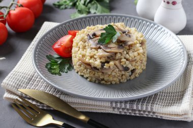 Bulgur garnish with champignons served with tomatoes on gray plate
