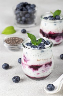 Chia pudding with blueberry and jam in two glass jars on light gray background, Healthy vegan breakfast, Vertical format