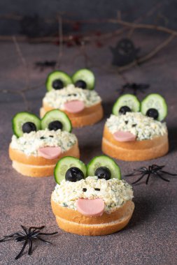 Salatalık, sosis, siyah zeytin, yumurta ve kurbağa şeklinde erimiş peynirli sandviç. Cadılar Bayramı partisi için yaratıcı bir fikir.