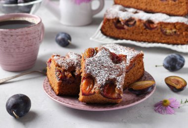 Pudra şekeri serpilmiş erikli ballı turta ve gri arka planda bir fincan kahve.