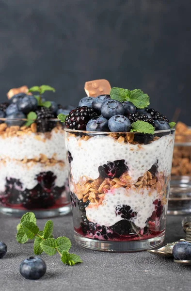 Chia pudding with blueberry and blackberry in two glass on dark gray background, Concept of healthy eating, dieting, fitness menu