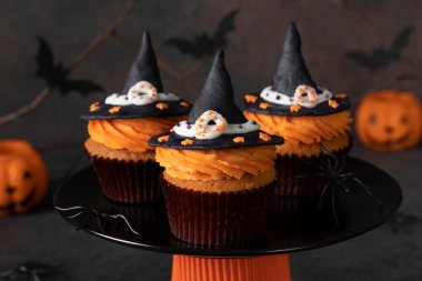 Cadılar Bayramı çörekleri kahverengi arka planda makarnadan yapılmış cadı şapkası örümceklerle ve yarasalarla süslenmiş Cadılar Bayramı 'nda çocuklar için şekerlemeler.