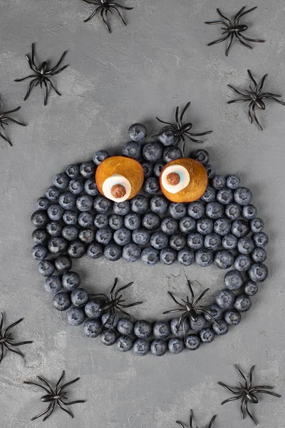 Monster of blueberries, plums and marshmallows for Halloween party on gray background, Top view