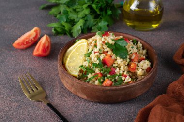 Geleneksel doğu salatası bulgur, domates ve kahverengi arka planda maydanoz ile Tabouleh
