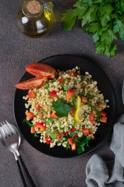 Kahverengi arka planda bulgur ve maydanozlu geleneksel doğu salatası Tabouleh, Üst görünüm, dikey görüntü