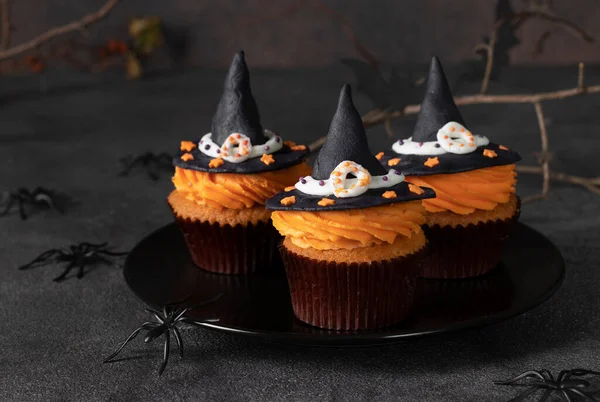 Halloween Party Treats - cupcakes decorated witch hat from mastic on gray background with spiders