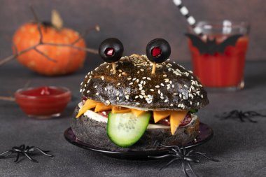 Siyah ekmekli, sosisli, peynirli, salatalıklı ve kahverengi gözlü canavar sandviçi.