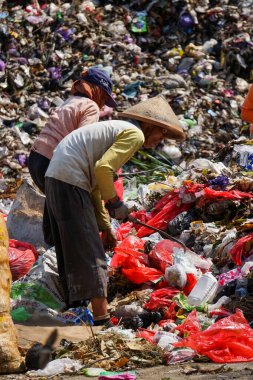 Ponorogo, Endonezya - 10 08 2021: Yaşlı bir adam ve kadın çöplükteki çöpleri ayırıyor ve onları çuvala dolduruyorlar..