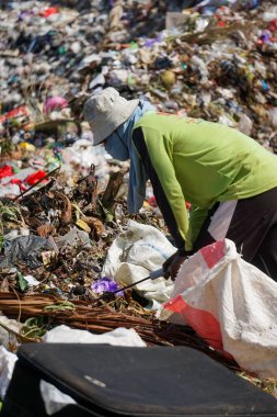 Ponorogo, Endonezya - 10 08 2021: Yeşil tişört giyen bir adam çöplükte geri dönüştürülebilecek çöpleri topluyor..