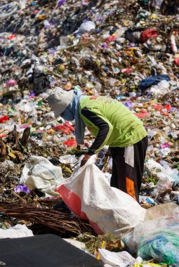 Ponorogo, Endonezya - 10 08 2021: Yeşil tişört giyen bir adam çöplükte geri dönüştürülebilecek atık topluyor..
