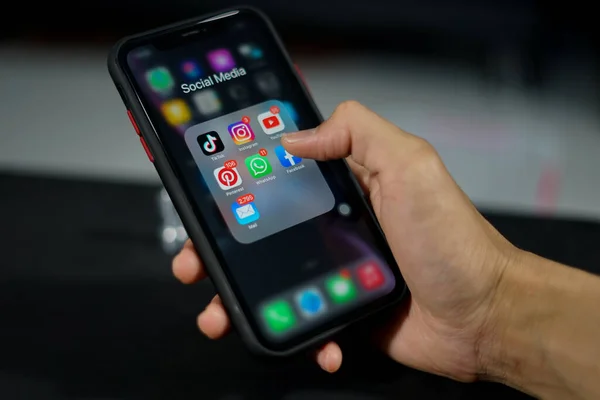 Ponorogo, Endonezya - 10 11 2021: Bir el sosyal medya klasörünü açan akıllı telefonu tutuyor. Uzaktan insanlarla iletişim kurmak için en çok kullanılan sosyal medya.  