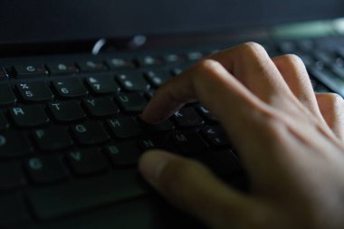 Ponorogo, Endonezya - 10 04 2021: Bilgisayarda bir şeyler yazan bir el. Kahverengi tenli masanın üstünde..