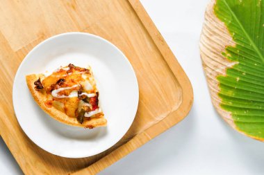 Üstten çekilen beyaz tabakta bir dilim pizza. Lezzetli bir İtalyan yemeği ve üzerine baharatlı sos..