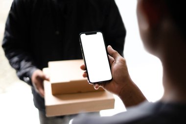 Nakitsiz ödeme jesti. Elinde telefon olan bir adam kuryeyle nakit ödemeden alışveriş yapıyor. Beyaz ekran telefon modeli. reklam için boş alan, ui ödeme tasarımı, vb..