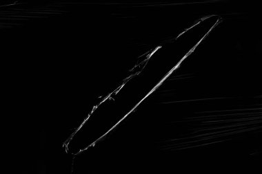 Siyah zemin üzerinde bir delik olan şeffaf plastik bir ambalaj. Kaplama ve efekt için gerçekçi yırtık plastik sargı dokusu. Yaratıcı ve dekoratif tasarım için buruşuk plastik desen.