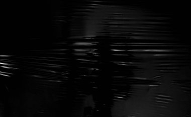 Siyah arka planda şeffaf bir plastik ambalaj. Kaplama ve etki için gerçekçi plastik ambalaj dokusu. Yaratıcı ve dekoratif tasarım için buruşuk plastik desen.