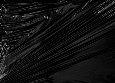 Siyah arka planda şeffaf bir plastik ambalaj. Kaplama ve etki için gerçekçi plastik ambalaj dokusu. Yaratıcı ve dekoratif tasarım için buruşuk plastik desen.