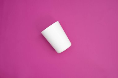 Pembe arka planda izole edilmiş tek bir beyaz kupa. En üst noktadan çekilen aletler. Grafikler ve model kullanımı için tek kullanımlık bulaşık takımı.