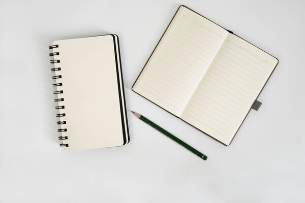 white desk with notebook, sketchbook, and pencil on top of it. a notebook mockup on desk as a workspace layout. office object isolated on white background.