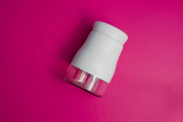 salt or pepper shaker in oblique view. seasoning powder container in white. food condiment shaker on pink background.