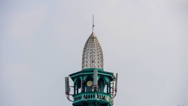 Geleneksel Endonezya mimarisine sahip bir cami minaresinin tepesinde. Minarenin hoparlörleri var. Namaza çağırıyorlar..