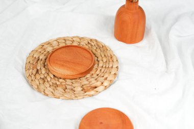 Ahşap bir paspası sergilemek için minimalist ürün platformu çekimi. Hasır hasırın üstündeki tahta minderin beyaz üzerine yerleştirilmesi..