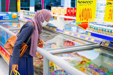 Ponorogo, Jawa Timur / Endonezya - 08 27 2020: Alışveriş merkezlerinde maske takan, malzeme, et ve baharat seçen kadınlar. Müslüman ev kadınları covid-19 salgını sırasında market alışverişi yapıyor..