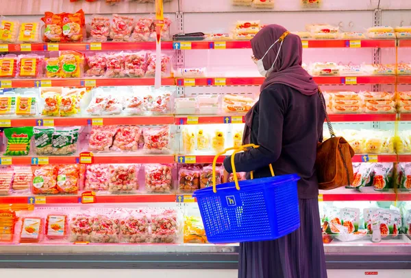 Ponorogo, Jawa Timur / Endonezya - 08 27 2020: alışveriş merkezlerinde meyve ve sebze seçen maskeli kadınlar. Müslüman ev kadınları covid-19 salgını sırasında market alışverişi yapıyor.