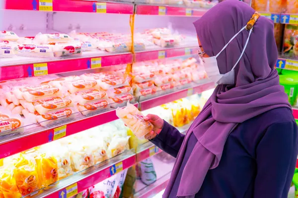 Ponorogo, Jawa Timur / Endonezya - 08 27 2020: alışveriş merkezlerinde meyve ve sebze seçen maskeli kadınlar. Müslüman ev kadınları covid-19 salgını sırasında market alışverişi yapıyor.