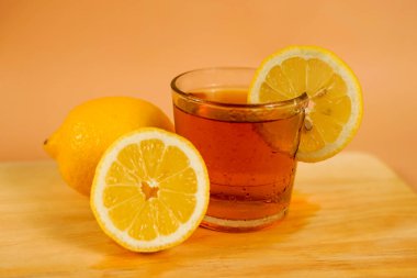 Tahta bir tabakta dilimlenmiş portakallarla süslenmiş bir fincan çay. Menü görüntüsü veya poster için uygun turuncu arkaplan içeren bir içecek menüsü.