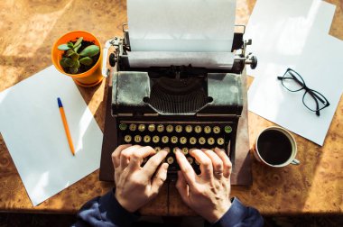 Erkek yazar kitabını eski bir antika daktiloya yazıyor. Eski bir antika daktilo.