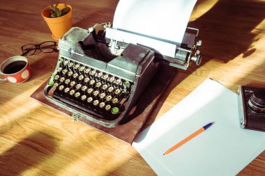 Masaüstüne makaleler ve kitaplar yazmak için eklenmiş kağıdı olan eski antik bir daktilo.