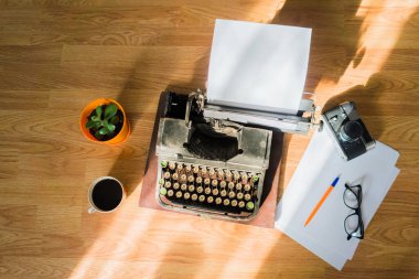 Masaüstüne makaleler ve kitaplar yazmak için eklenmiş kağıdı olan eski antik bir daktilo.