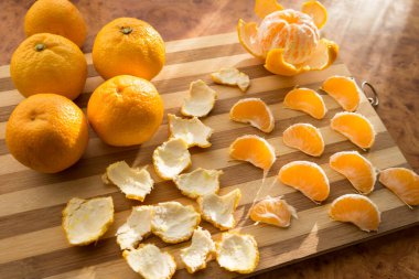 Mandalina ve mandalina dilimleri ahşap tahtaların üstünde..