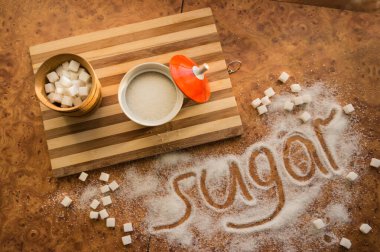 Masadaki yazı şekeri, şeker kasesindeki rafine şeker..