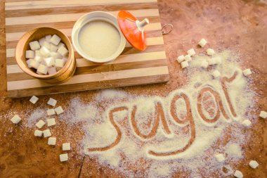 Masadaki yazı şekeri, şeker kasesindeki rafine şeker..