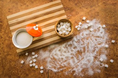 Şeker ve rafine şeker masanın üstüne saçılmış..