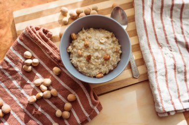 Sağlıklı, besleyici ve besleyici yulaf ezmesi. Masanın üstünde gri bir tabakta fındıklı..
