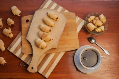 Elma reçelli kruvasan ve ahşap arka planda bir fincan kahve..