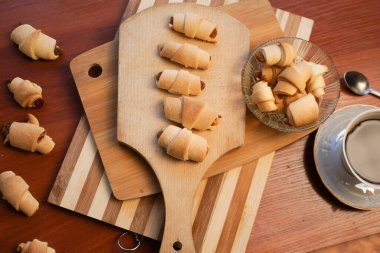 Elma reçelli kruvasan ve ahşap arka planda bir fincan kahve..