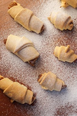 Ahşap zemin üzerine pudra şekeri serpiştirilmiş elma reçeli kruvasanlar..