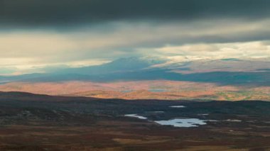 İsveç Pieljekaise Ulusal Parkı 'nda sonbaharda zaman kaybı, karla kaplı dağlar, gökyüzünde hareket eden bulutlar, önde göller, Kuzey İsveç