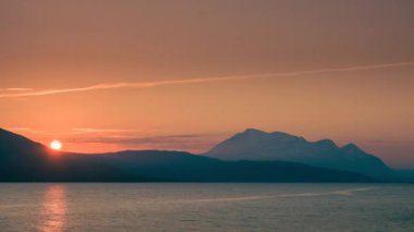 Time lapse of sunset in mountain landscape in Swedish Stora Sjoefallet national park, snow covered mountains in the back, clouds moving in the sky, lake in the front, North Sweden