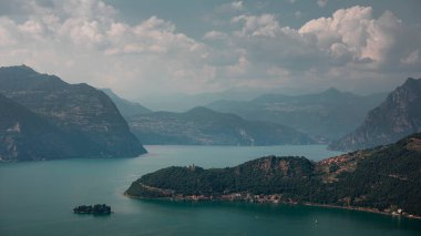 Iseo Gölü 'nde Monte Isola adasıyla dağ manzarası, arka planda dağlar, gökyüzünde bulutlar, İtalya