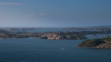 Coast with rock islands at village Fjaellbacka with windsurfer from above during sunny blue sky day in Sweden