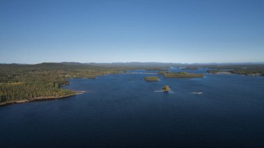 Dalarna 'da mavi gökyüzü, İsveç' te gökyüzü bulutları ve Siljan Gölü 'nde adaları olan yeşil orman ve kıyı.