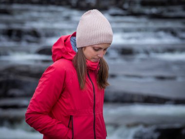 Sonbaharda Trappstegsforsen Şelalesi 'nde bir kadın. İsveç' te Laponya 'da Wilderness Yolu boyunca. Gökyüzünde bulutlar.